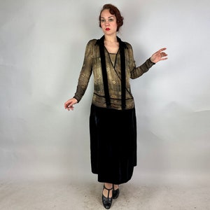 May include: A vintage-style dress with a black velvet skirt and a sheer, gold-toned top with a floral pattern. The top features a V-neckline and a wrap-style design.