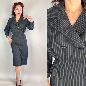 May include: A dark gray pinstripe suit featuring a double-breasted blazer and a knee-length pencil skirt. The blazer has a notched collar and two rows of buttons. The suit is a classic style, suitable for professional or formal occasions.