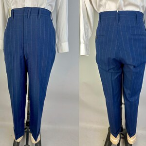 Puede incluir: Pantalones de talle alto en color azul profundo con finas rayas verticales. Los pantalones tienen una cintura estructurada con trabillas para cintur&oacute;n, cierre de cremallera frontal y dobladillos con vuelta. La vista trasera muestra dos bolsillos.