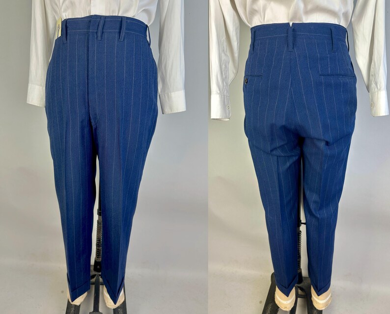 Puede incluir: Pantalones de talle alto en color azul profundo con finas rayas verticales. Los pantalones tienen una cintura estructurada con trabillas para cintur&oacute;n, cierre de cremallera frontal y dobladillos con vuelta. La vista trasera muestra dos bolsillos.