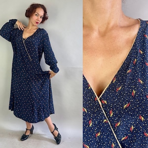 Può includere: Un abito lungo blu navy a maniche lunghe con stampa floreale gialla e rossa. L'abito ha una scollatura a V e una chiusura avvolgente.