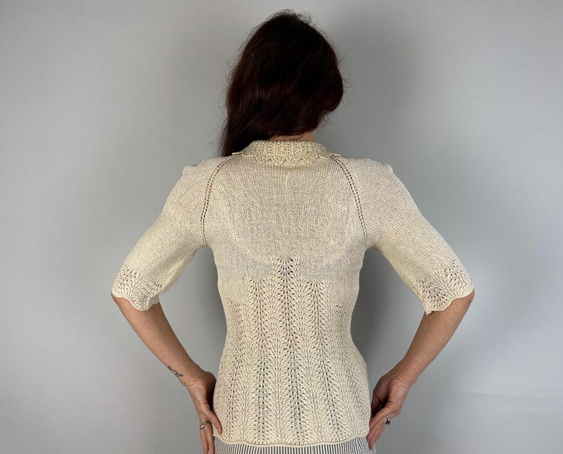 May include: A white crocheted sweater with a delicate lace pattern and short sleeves.