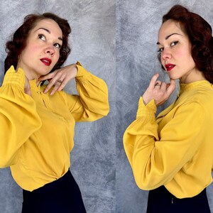 May include: A white ceramic mug with a black handle and the text "But First, Coffee" in a bold, black font. The mug is set against a blurred background, suggesting a cozy setting.