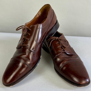 Può includere: Un paio di scarpe marroni in pelle con lacci e punta a cap.