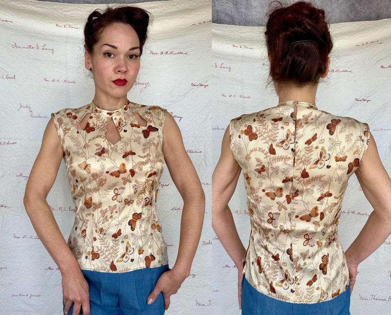 May include: A sleeveless, cream-colored top with a butterfly and foliage pattern. The top features a keyhole neckline and a high collar. The butterflies are in shades of brown and orange. The top is made of a silky material.