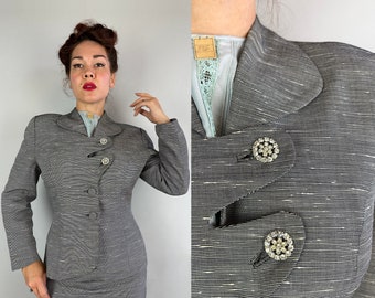 May include: A gray and white striped blazer with a collar and three rhinestone buttons. The blazer has a fitted silhouette and a slightly cropped length.