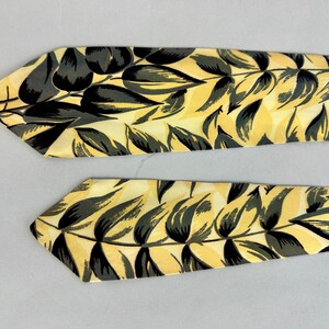 May include: Two yellow and black patterned neckties with a leaf design.