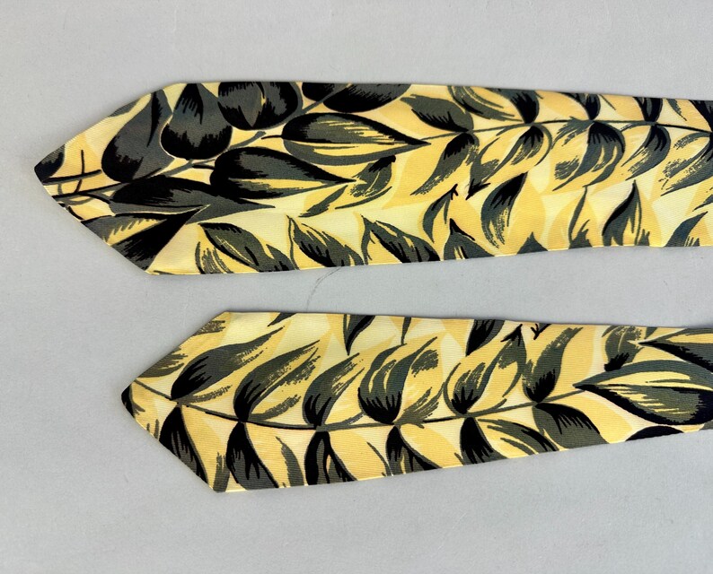May include: Two yellow and black patterned neckties with a leaf design.