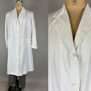 May include: A white lab coat with long sleeves, a button-up front, and two pockets. The coat is on a mannequin.