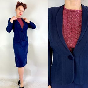 Può includere: Un tailleur gonna blu navy vintage. Il completo include un blazer con chiusura a bottone singolo e una gonna abbinata al ginocchio. Il blazer presenta dettagli di cuciture verticali. Un top in maglia bordeaux è indossato sotto.