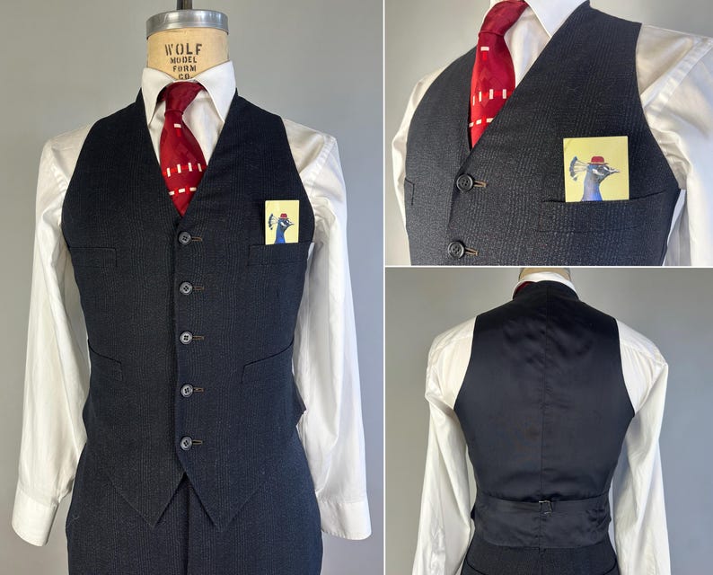 May include: A dark charcoal gray pinstriped vest featuring a five-button front closure, two welt pockets, and a solid black back panel with an adjustable strap. The vest is worn over a white collared shirt with a red tie and a peacock pocket square.