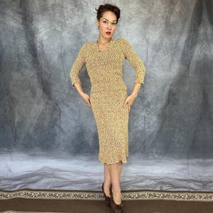 May include: A vintage two-piece knit set in a speckled pattern of yellow and red. The set includes a long-sleeved top and a knee-length skirt. The model is wearing brown patterned heels.