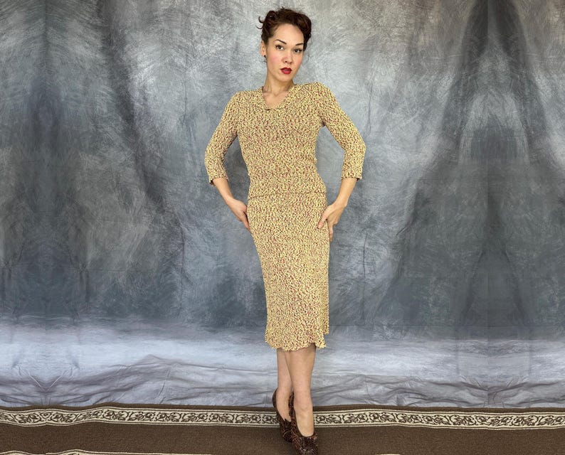 May include: A vintage two-piece knit set in a speckled pattern of yellow and red. The set includes a long-sleeved top and a knee-length skirt. The model is wearing brown patterned heels.