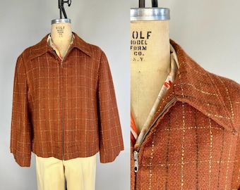 Può includere: Una giacca marrone e oro con chiusura a zip. La giacca ha un colletto e maniche lunghe. L'etichetta sulla giacca recita "Kolf Model Form Co. N.Y."