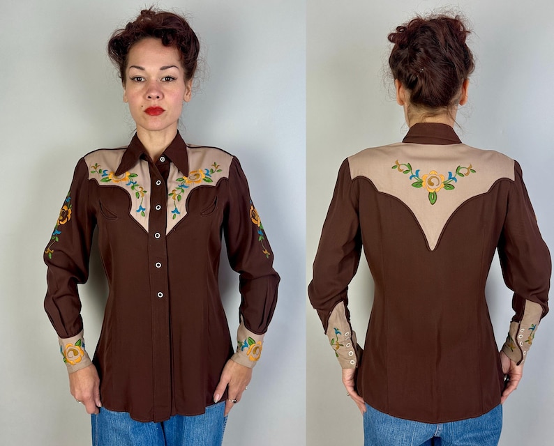 May include: A long-sleeved button-down shirt in dark brown featuring a tan yoke and cuffs. The shirt is decorated with embroidered floral patterns in yellow, blue, and green on the front yoke, sleeves, cuffs, and the back yoke area.