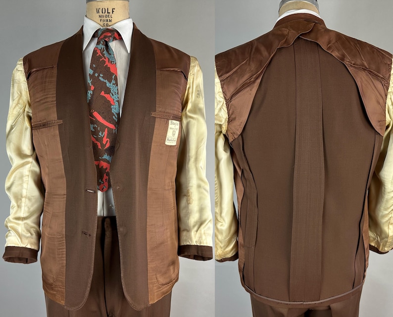 May include: A two-piece brown suit with a white shirt and patterned tie. The suit jacket has a notched lapel and two buttons. The interior lining is a light beige color. The suit is displayed on a mannequin.