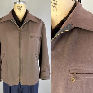 May include: A brown zip-up jacket with a stand-up collar and two pockets. The jacket has a zipper closure and a gold zipper pull.