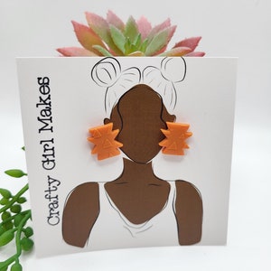 May include: Orange geometric stud earrings on a white card with a line drawing of a person wearing the earrings. The card has the text "Crafty Girl Makes" on it.