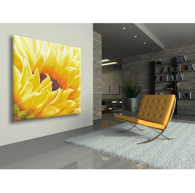 May include: A close-up of a yellow sunflower painting with a brown center. The painting is on a canvas and is hanging on a white wall.