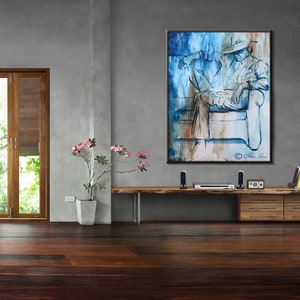 Puede incluir: Una pintura abstracta azul y marr&oacute;n de una persona sentada en un sof&aacute;. La pintura est&aacute; enmarcada y colgada en una pared gris.