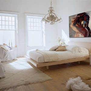K&ouml;nnte beinhalten: Ein wei&szlig;es Schlafzimmer mit einem gro&szlig;en Bett, einem wei&szlig;en Teppich und einem Gem&auml;lde von zwei sich umarmenden Personen an der Wand. Das Bett hat einen wei&szlig;en Bettbezug und einen Holzrahmen. Der Teppich ist hellbeige und hat ein Rautenmuster. Das Gem&auml;lde ist im modernen abstrakten Stil gehalten und in Braun- und Rott&ouml;nen gehalten.