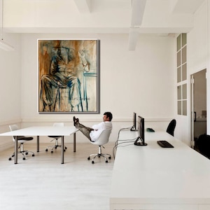 May include: A white office with a large abstract painting of a person sitting in a chair. The painting is in shades of brown, blue, and white. The painting is hanging on a white wall. There is a white desk in the foreground with a person sitting in a chair with their feet up on the desk. The desk has a computer monitor and a keyboard on it. The room has a white ceiling and white walls.