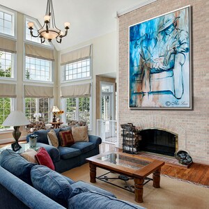 Puede incluir: Una sala de estar con una gran pintura abstracta de una persona sentada en un sof&aacute;. La pintura est&aacute; en tonos de azul, blanco y marr&oacute;n. La habitaci&oacute;n tiene una chimenea, una mesa de caf&eacute; y un sof&aacute; con cojines azules.
