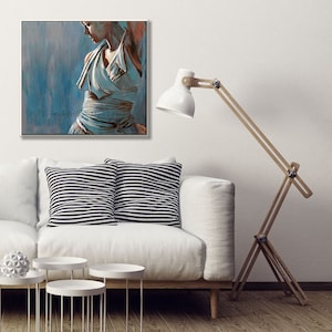 May include: A painting of a woman in a white dress with a blue background. The woman is standing with her head tilted down and her arms crossed. The painting is framed and hanging on a white wall.