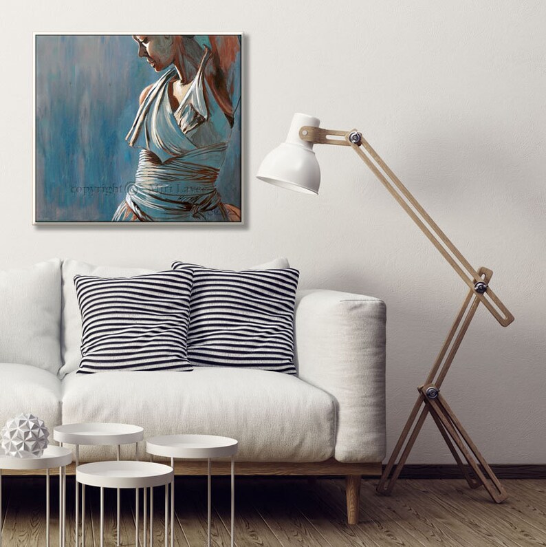 May include: A painting of a woman in a white dress with a blue background. The woman is standing with her head tilted down and her arms crossed. The painting is framed and hanging on a white wall.