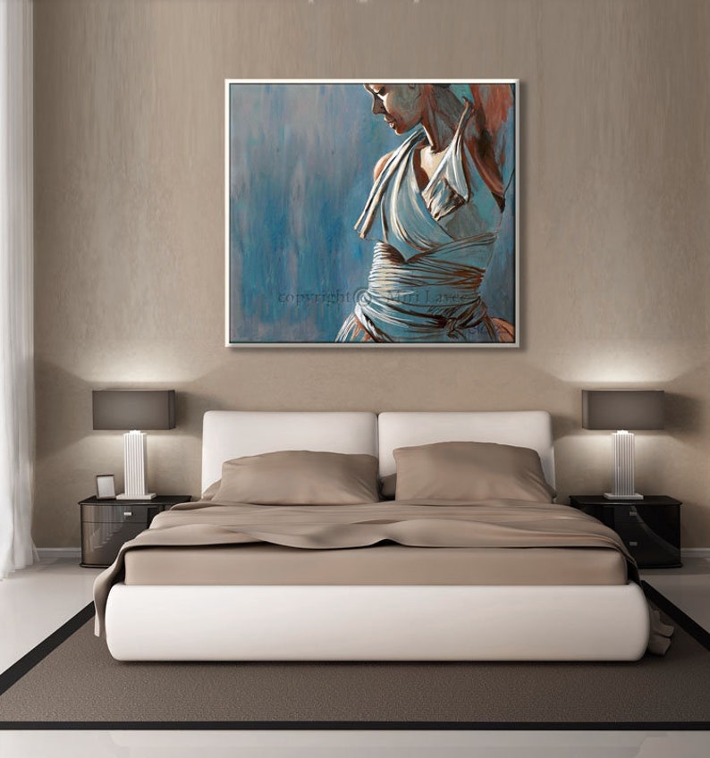 May include: A painting of a woman in a white dress, standing in a blue and gray background. The painting is framed in a white frame and is hanging on a wall above a bed.