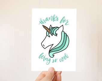 Puede incluir: Un unicornio blanco con una crin de color azul turquesa y un cuerno dorado. El unicornio mira hacia la izquierda. El texto "thanks for being so cool" está escrito en letras cursivas de color azul turquesa.