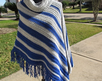 Puede incluir: Un poncho de crochet a rayas grises y azules con cuello de tortuga y ribete de flecos.