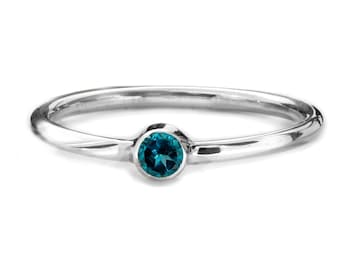 May include: A simple silver band ring with a small, round, teal blue gemstone.