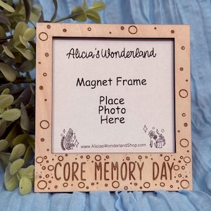 May include: A wooden magnet frame with the text "Alicia's Wonderland," "Magnet Frame," and "Place Photo Here." The frame has a light brown color with decorative circles and the words "CORE MEMORY DAY" at the bottom. The website address is also visible.