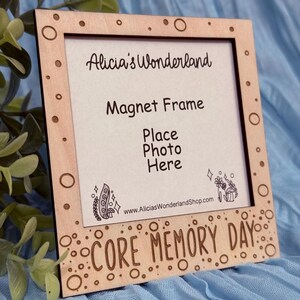 May include: A wooden magnet frame with the text "Alicia's Wonderland", "Magnet Frame", and "Core Memory Day". The frame has a rectangular opening for a photo and decorative circles.