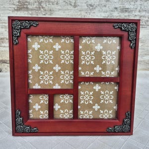 May include: A red wooden multi-photo frame with a decorative floral corner design. The frame has multiple openings with a beige and white floral pattern background. A decorative home decor item.
