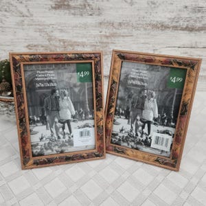 May include: Two decorative photo frames with a brown and gold floral design border. Each frame holds a black and white photo and has a green price tag. The frames are 5x7 inches (13x18cm).