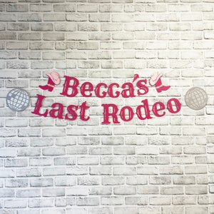 以下が含まれることがあります： 白いレンガの壁に、「Becca's Last Rodeo」と書かれたピンクと赤の横断幕。横断幕には、ピンクのウエスタンハットとブーツが描かれている。