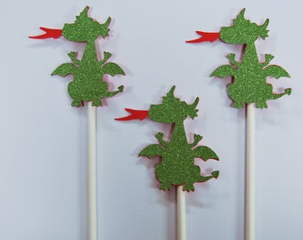 May include: Three green glitter dragon cupcake toppers with red glitter tongues. The dragons are on white sticks.