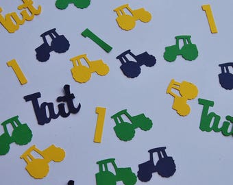 May include: Green, yellow, and blue paper cutouts of tractors, the number one, and the name "Tait" scattered on a white background.