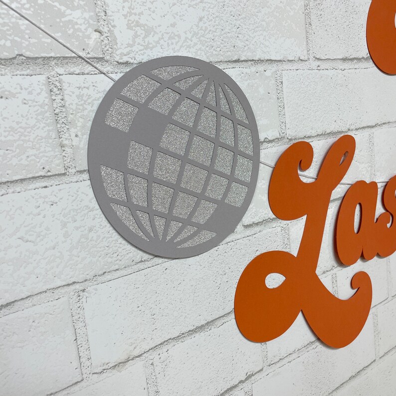 May include: A silver glitter disco ball banner with the word "Last" in orange letters.