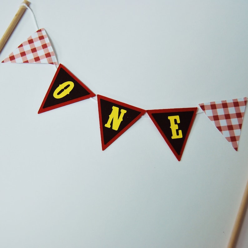 May include: A red and white gingham banner with black triangles that spell out "ONE" in yellow letters.