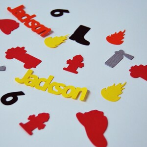 May include: Yellow paper cutouts of the name "Jackson" and the number "6" with red, orange, and yellow flames, a red fire truck, a red fire hydrant, a black boot, and a gray fire extinguisher.