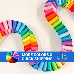 May include: A long, winding paper chain garland constructed from interlocking loops of paper in a vibrant rainbow spectrum, featuring shades of red, orange, yellow, green, blue, and purple, arranged in a continuous, flowing, serpentine pattern.