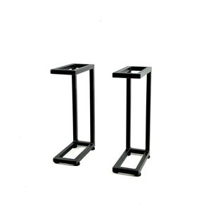 May include: Two black metal plant stands with a simple, modern design. Each stand has a rectangular base and a square top.