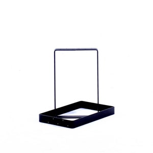 Peut inclure: Un support en m&eacute;tal noir avec une base rectangulaire et un cadre carr&eacute;. Le support est con&ccedil;u pour tenir des objets comme des plantes ou d'autres objets d&eacute;coratifs.