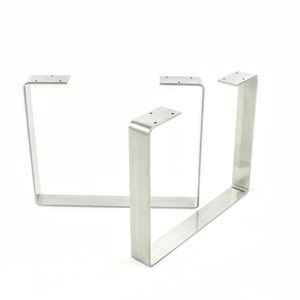 May include: Three silver metal table legs with a square shape and a flat top.