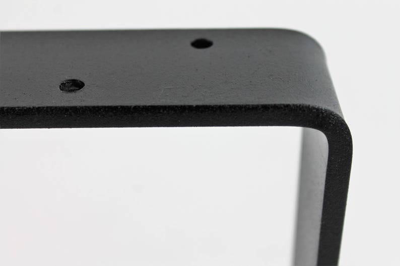 Peut inclure: &Eacute;querre d'&eacute;tag&egrave;re en m&eacute;tal noir de forme carr&eacute;e avec des bords arrondis. L'&eacute;querre comporte trois trous pour le montage.