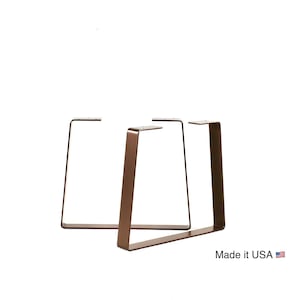 May include: Three metal table legs in a triangular shape. The legs are made of a dark brown metal and are connected at the top. The legs are made in the USA.