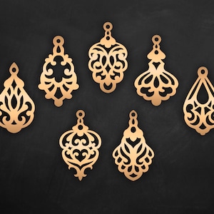 May include: Set of eight gold-colored metal earring charms with intricate filigree designs. Each charm features a unique pattern of swirls and curves.